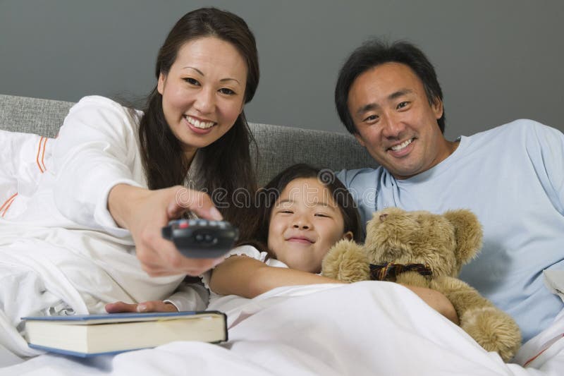 Family Watching TV Together In Bed stock image Family Watching TV Together In Bed stock image
