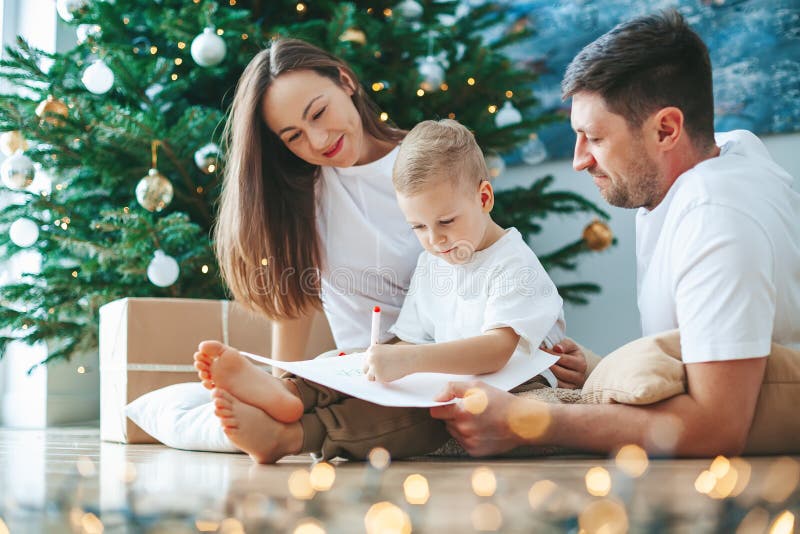 Family writing a letter to Santa Claus near the Christmas tree