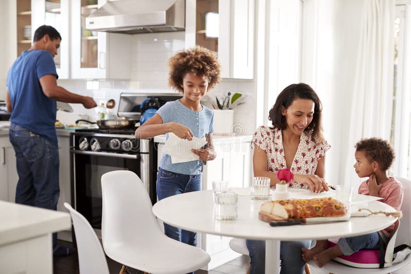 Família afro-americano nova que prepara uma refeição junto em sua cozinha