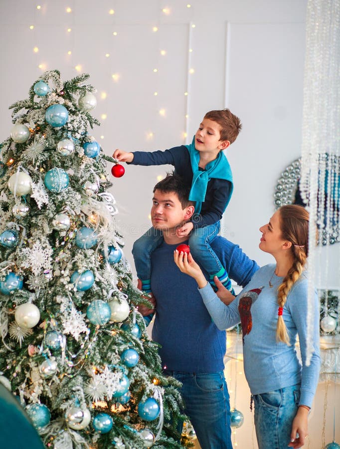 A família amigável feliz que decora a árvore de Natal tem o divertimento imagem de stock A família amigável feliz que decora a árvore de Natal tem o divertimento imagem de stock