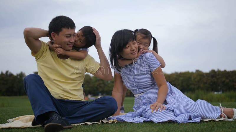 Família asiática bonita com os irmãos que relaxam no parque