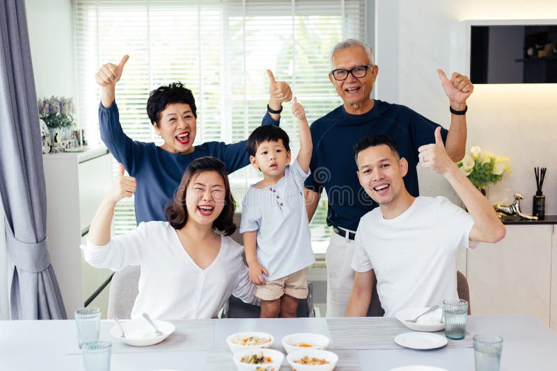 Família asiática prolongada de três gerações que têm um togethe da refeição