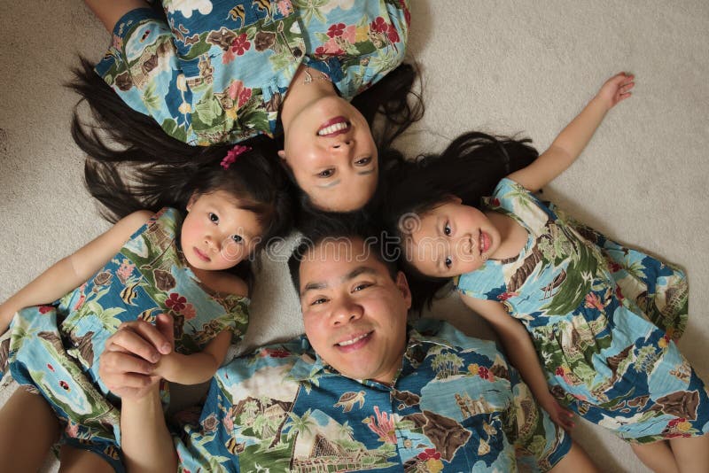 Família asiática que coloca no sorriso do assoalho