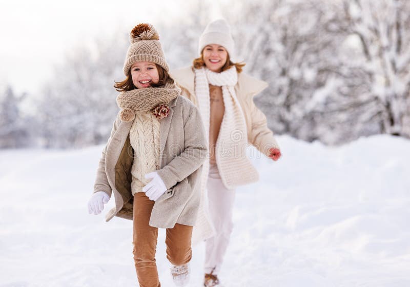 Família ativa feliz mãe e filha pequena se divertem no parque de inverno jogando catchup no dia da neve