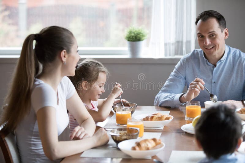 Família atrativa feliz que tem o assento saudável do café da manhã no fotografia de stock Família atrativa feliz que tem o assento saudável do café da manhã no fotografia de stock