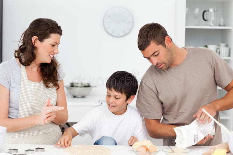 Caucasian family cooking biscuits together in the kitchen at home. Caucasian family cooking biscuits together in the kitchen at home