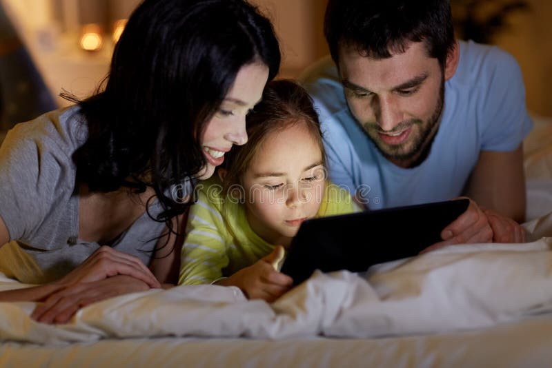 Família com pc comprimido na cama à noite em casa imagem de stock