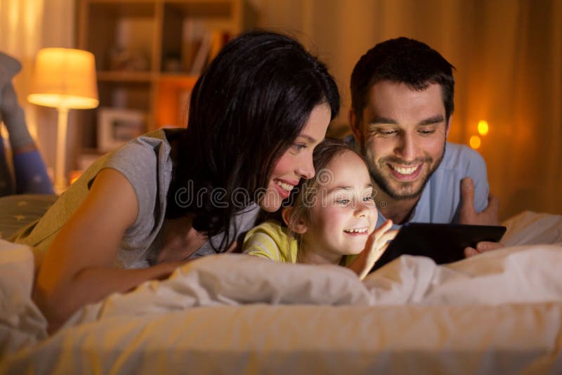 Família com pc comprimido na cama à noite em casa foto de stock