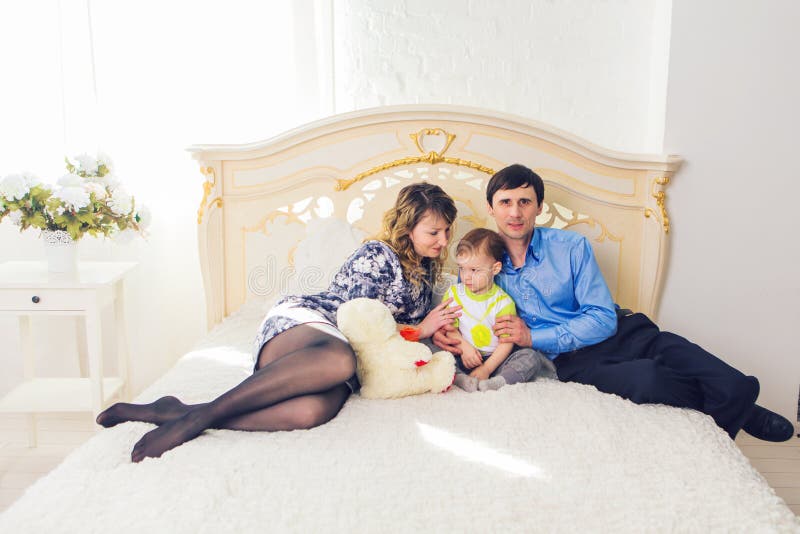 Família, conceito da paternidade e das crianças - mãe feliz, pai e filho que jogam junto com o urso de peluche na cama dentro foto de stock Família, conceito da paternidade e das crianças - mãe feliz, pai e filho que jogam junto com o urso de peluche na cama dentro foto de stock