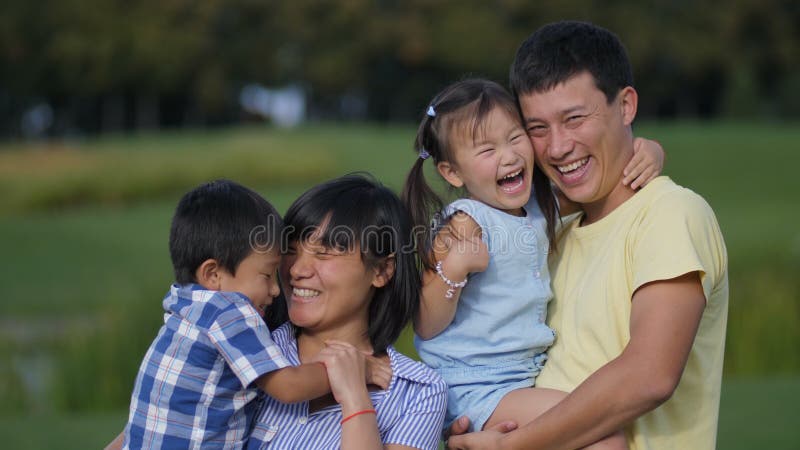 Família de quatro pessoas asiática entusiasmado que ri no parque
