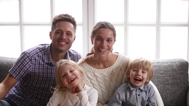 Família de sorriso alegre com as duas crianças que riem olhando a câmera