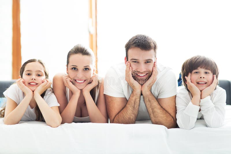 Família de sorriso na cama imagem de stock royalty free Família de sorriso na cama imagem de stock royalty free