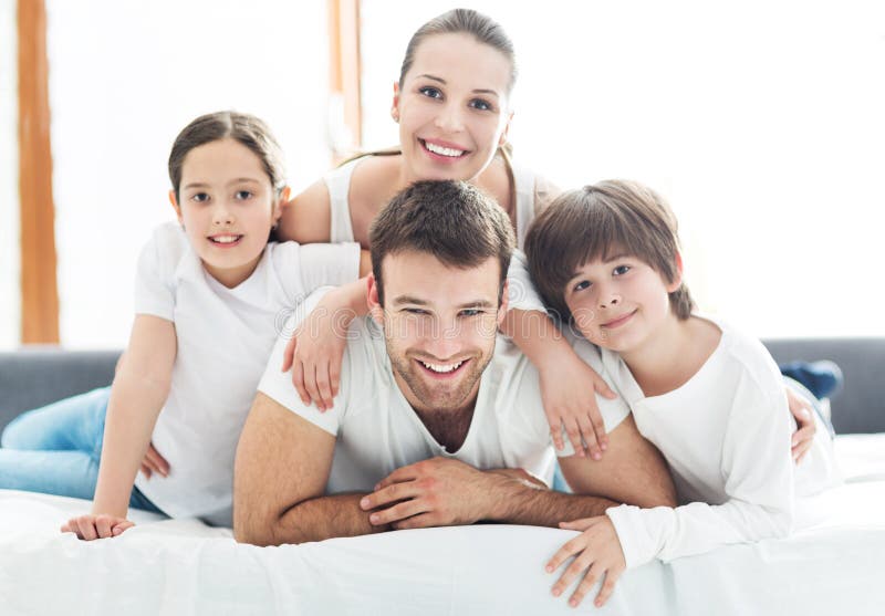 Família de sorriso na cama fotografia de stock Família de sorriso na cama fotografia de stock