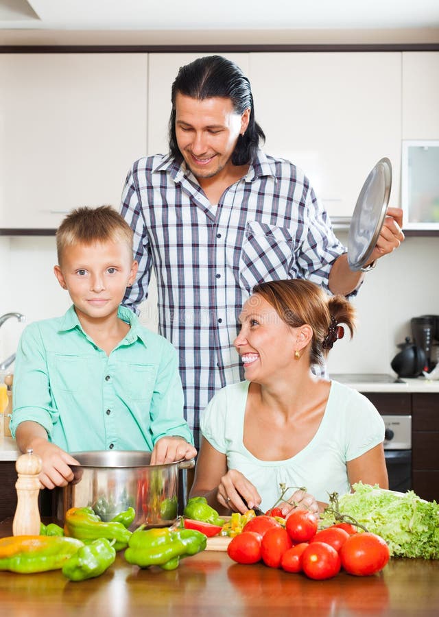 Família de sorriso que cozinha vegetais imagem de stock Família de sorriso que cozinha vegetais imagem de stock