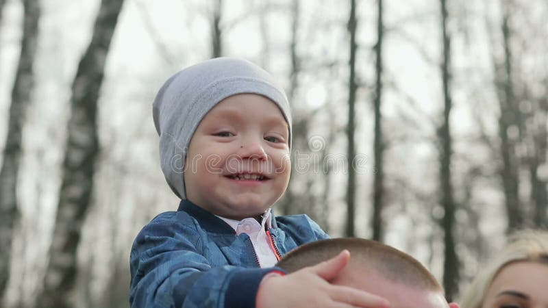 Família de três feliz que anda na primavera parque