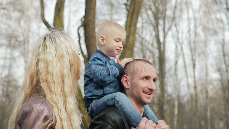 Família de três feliz que anda na primavera parque