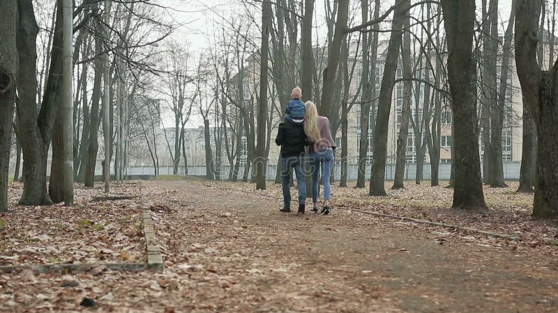 Família de três feliz que anda na primavera parque