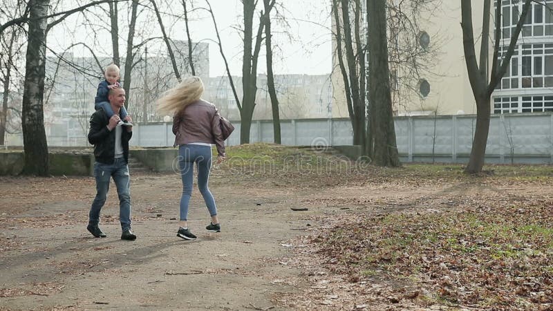 Família de três feliz que anda na primavera parque