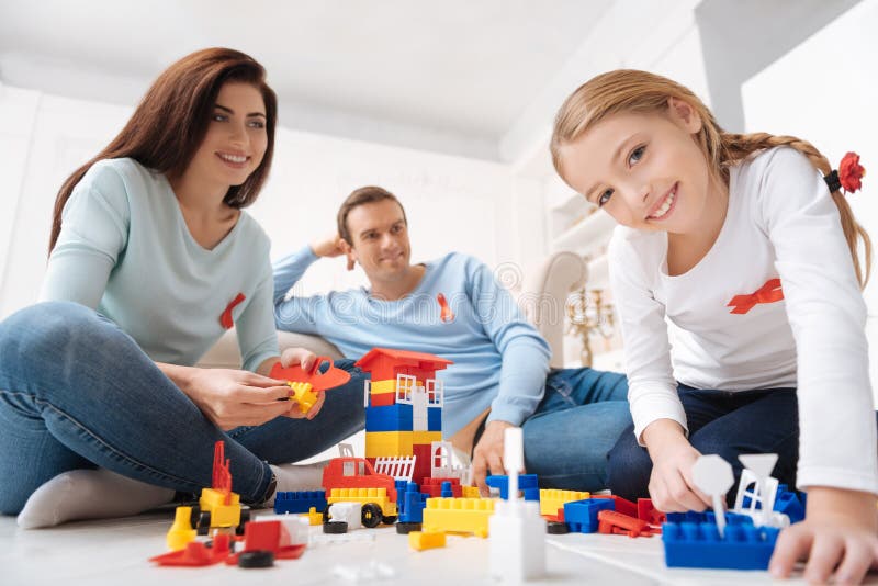 Família deleitada alegre que senta-se em torno do grupo do meccano foto de stock Família deleitada alegre que senta-se em torno do grupo do meccano foto de stock