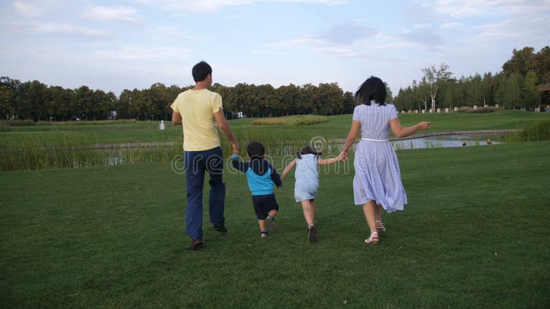 Família despreocupada com as crianças que correm através do parque