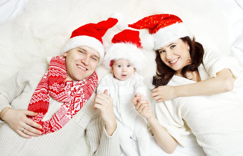 Família do Natal com o bebê em chapéus vermelhos. fotografia de stock royalty free Família do Natal com o bebê em chapéus vermelhos. fotografia de stock royalty free