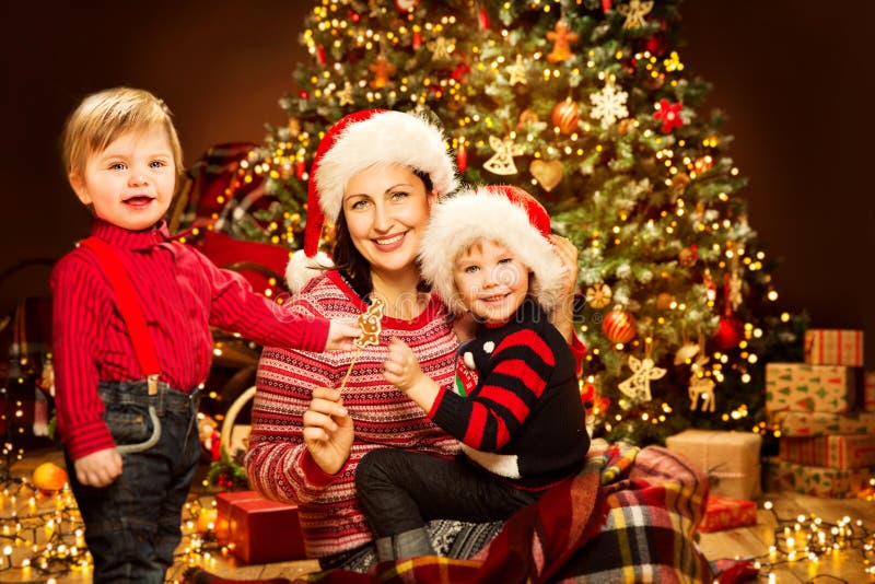 Família do Natal, mãe com parte dianteira das crianças de luzes da árvore do Xmas, mamã feliz e bebê imagens de stock royalty free Família do Natal, mãe com parte dianteira das crianças de luzes da árvore do Xmas, mamã feliz e bebê imagens de stock royalty free