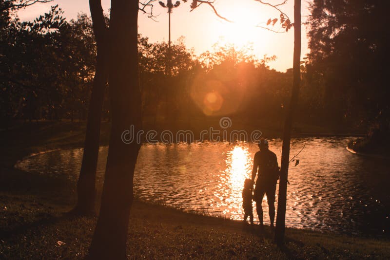 Família dos pais paizinho e das silhuetas das crianças da filha no fundo bonito do ar livre da natureza do por do sol imagem de stock Família dos pais paizinho e das silhuetas das crianças da filha no fundo bonito do ar livre da natureza do por do sol imagem de stock