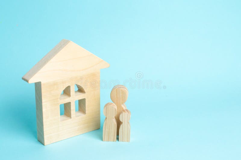 A família está estando perto da casa As figuras de madeira das pessoas estão perto de uma casa de madeira O conceito de um par no imagens de stock royalty free A família está estando perto da casa As figuras de madeira das pessoas estão perto de uma casa de madeira O conceito de um par no imagens de stock royalty free
