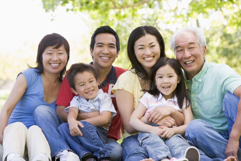 Família extensa que senta ao ar livre o sorriso imagens de stock Família extensa que senta ao ar livre o sorriso imagens de stock