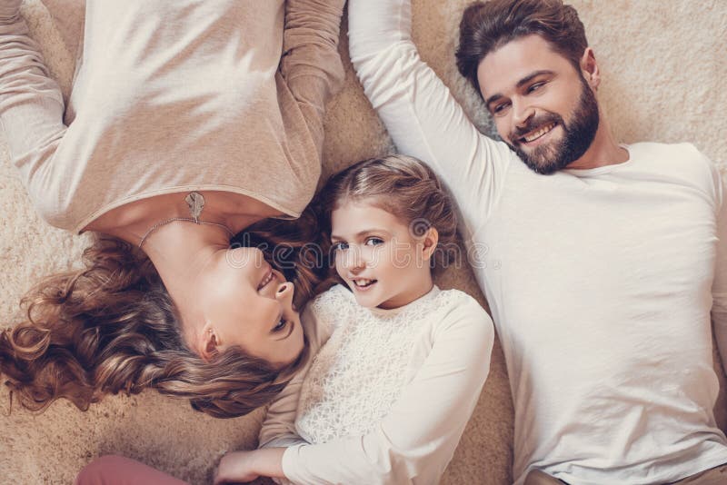 Família feliz com a uma criança que encontra-se junto no tapete fotos de stock royalty free Família feliz com a uma criança que encontra-se junto no tapete fotos de stock royalty free