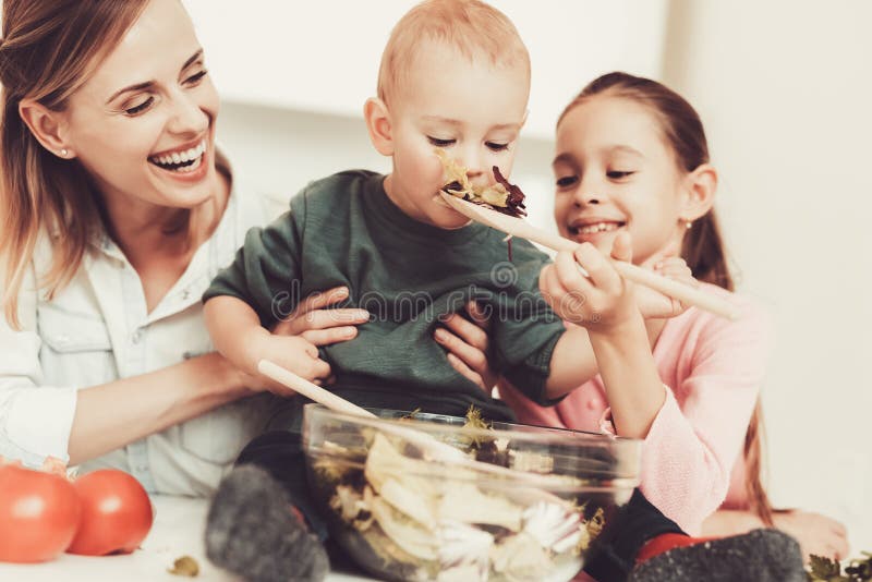 A família feliz está preparando uma salada na cozinha foto de stock royalty free A família feliz está preparando uma salada na cozinha foto de stock royalty free