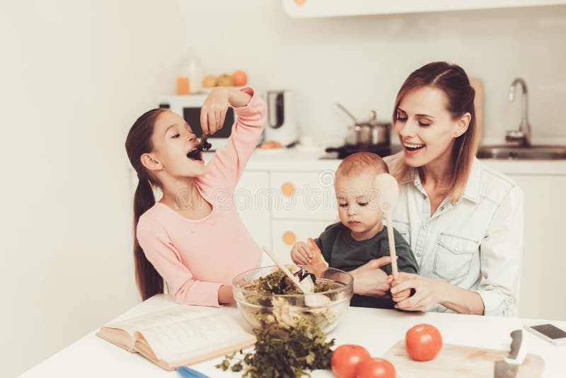 A família feliz está preparando uma salada na cozinha foto de stock royalty free A família feliz está preparando uma salada na cozinha foto de stock royalty free