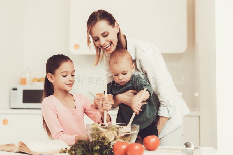 A família feliz está preparando uma salada na cozinha imagem de stock royalty free A família feliz está preparando uma salada na cozinha imagem de stock royalty free