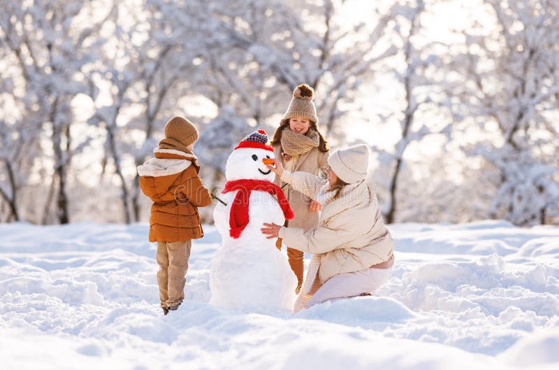 Família feliz mãe e dois filhos pequenos fazendo boneco de neve juntos no parque de inverno ao ar livre