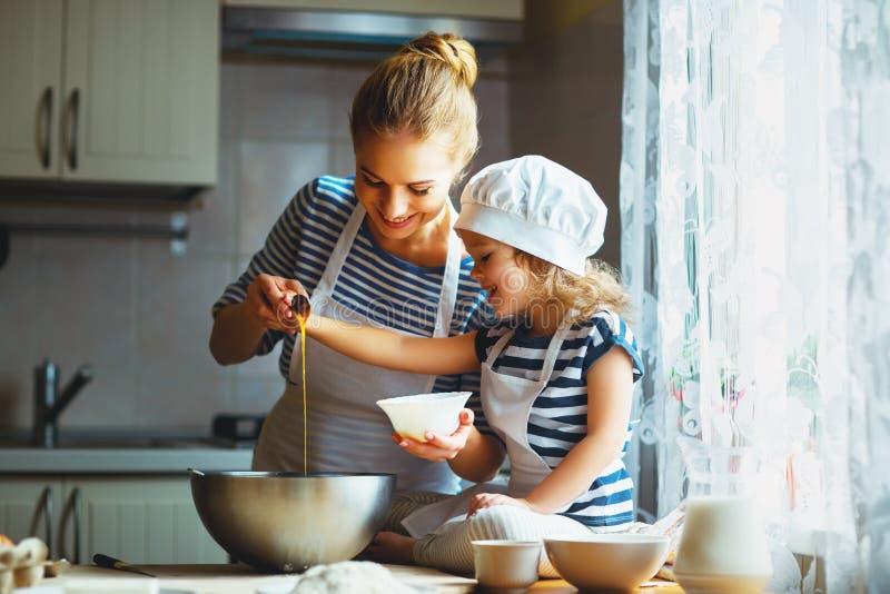 Família feliz na cozinha a mãe e a criança que preparam a massa, cozem