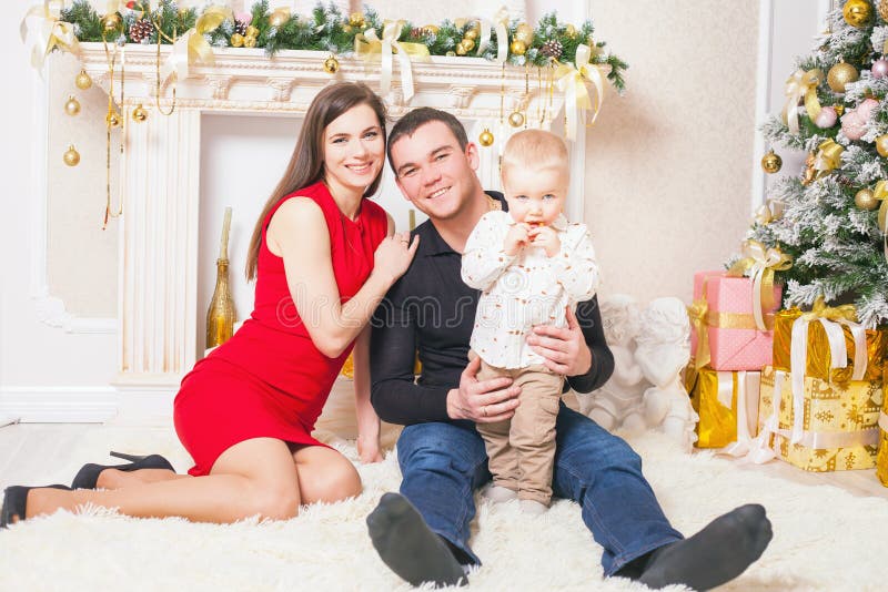 Família feliz na Noite de Natal que senta-se junto perto da chaminé foto de stock royalty free Família feliz na Noite de Natal que senta-se junto perto da chaminé foto de stock royalty free