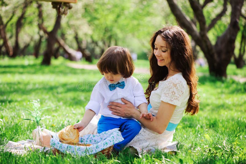 Família feliz no piquenique para o dia de mães Filho da mamã e da criança que come os doces exteriores na mola ou no verão foto de stock Família feliz no piquenique para o dia de mães Filho da mamã e da criança que come os doces exteriores na mola ou no verão foto de stock