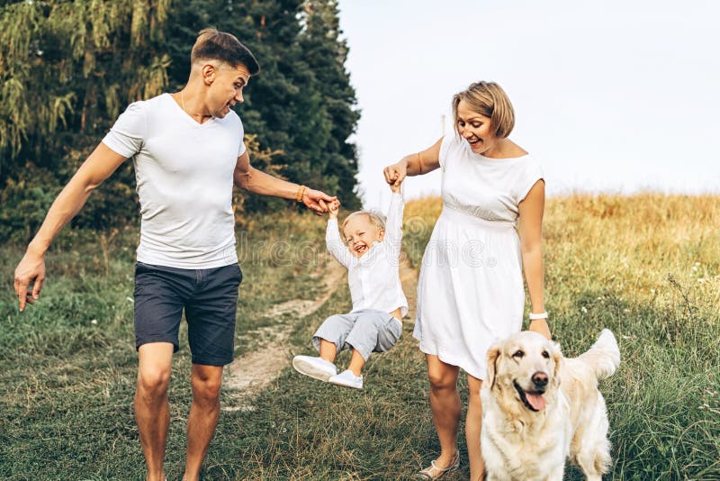 A família feliz nova com cão tem o divertimento exterior foto de stock A família feliz nova com cão tem o divertimento exterior foto de stock