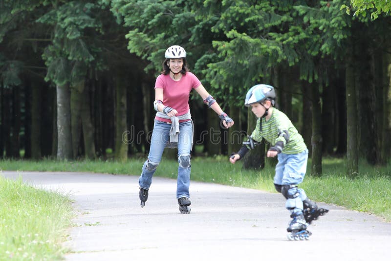 Família feliz que aprende montar em rollerblades fotografia de stock royalty free Família feliz que aprende montar em rollerblades fotografia de stock royalty free