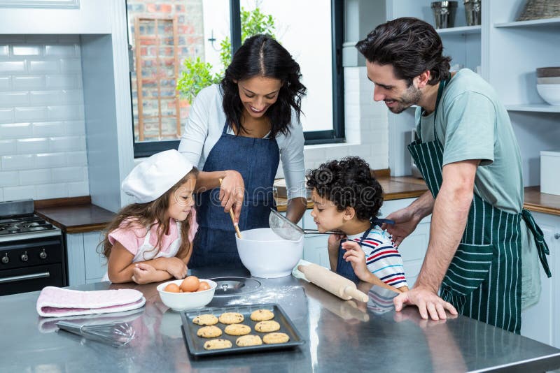 Happy family cooking biscuits together in kitchen at home. Happy family cooking biscuits together in kitchen at home