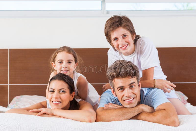 Família feliz que encontra-se em uma cama imagens de stock Família feliz que encontra-se em uma cama imagens de stock