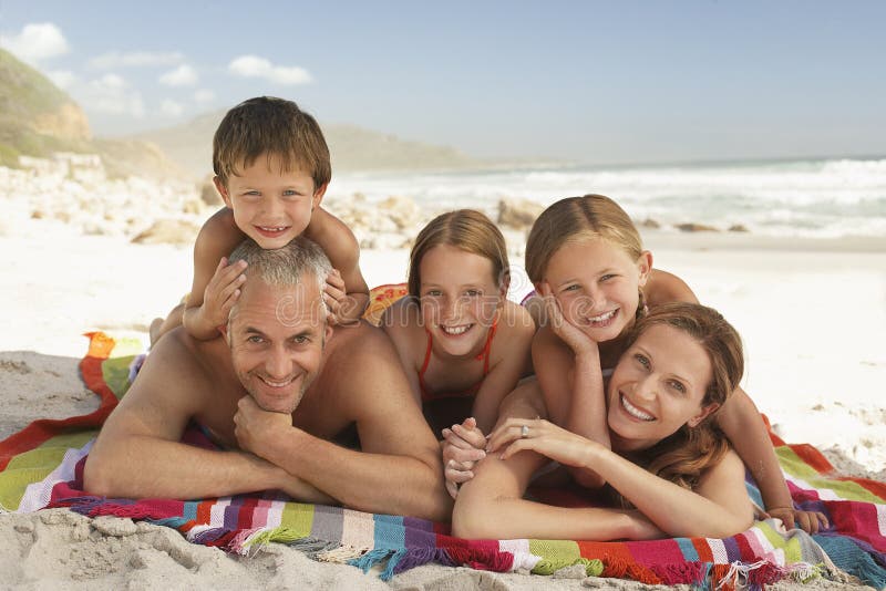 Família feliz que encontra-se junto na praia imagem de stock Família feliz que encontra-se junto na praia imagem de stock