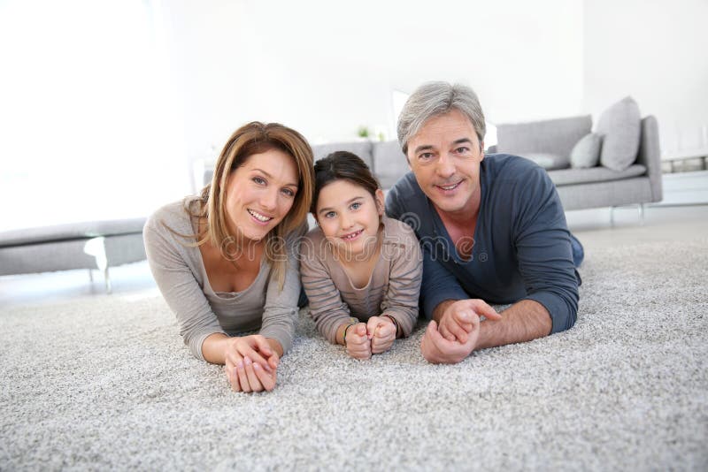 Família feliz que encontra-se no assoalho de tapete imagem de stock Família feliz que encontra-se no assoalho de tapete imagem de stock