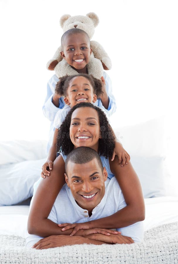 Família feliz que tem o divertimento encontrar-se para baixo na cama foto de stock royalty free Família feliz que tem o divertimento encontrar-se para baixo na cama foto de stock royalty free
