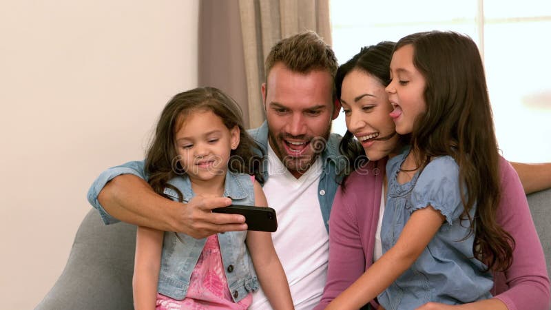 Família feliz que toma o selfie no sofá