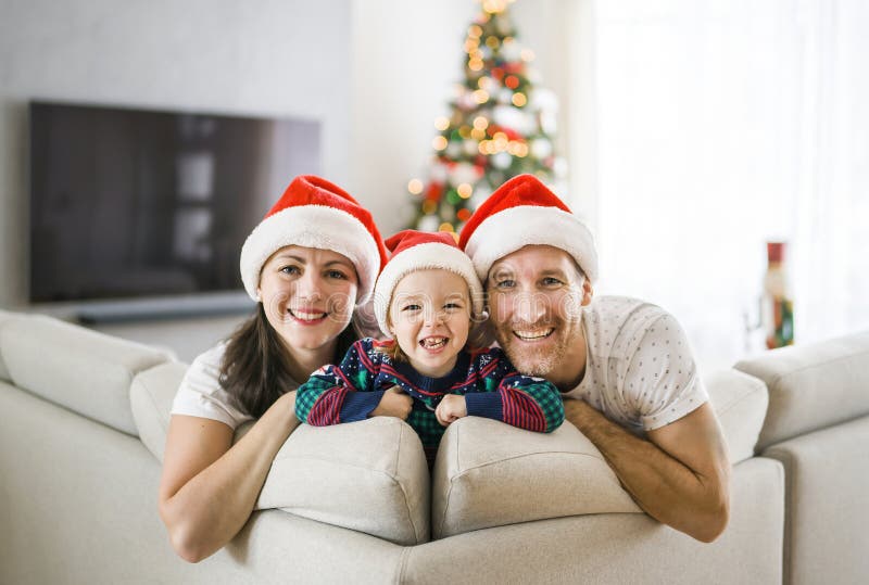 Família feliz sentada no sofá com sua bebê no natal imagens de stock royalty free