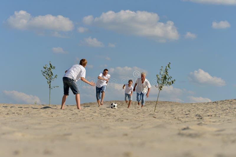 Família jogando futebol na praia no verão fotografia de stock