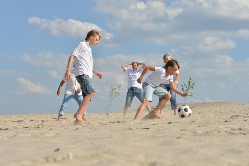 Família jogando futebol na praia no verão imagem de stock royalty free