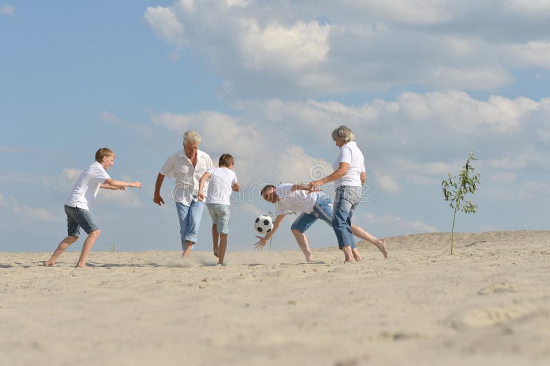 Família jogando futebol na praia no verão imagens de stock