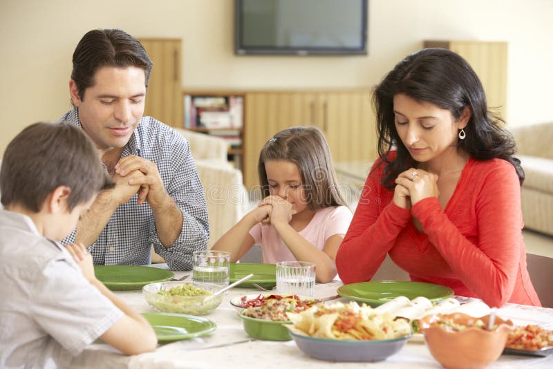 Família latino-americano nova que diz orações antes da refeição em casa foto de stock Família latino-americano nova que diz orações antes da refeição em casa foto de stock